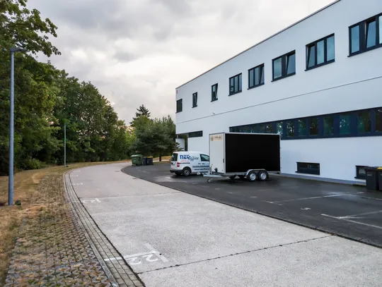 Das Bürogebäude in der Johanna-Waescher-Straße 5 von außen, davor ein NET.Office-Firmenwagen mit Anhänger