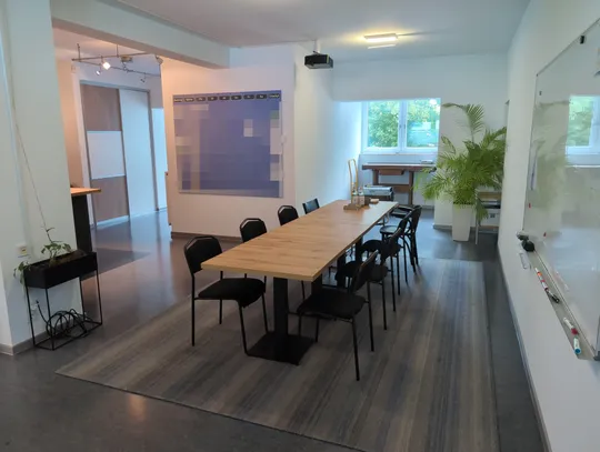 Besprechungsraum mit langem Holztisch, Whiteboard und Beamer